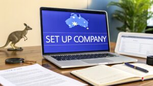 Laptop screen displaying “Set Up Company” with an Australia map graphic, surrounded by documents, a notebook, and office items on a desk.